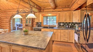 A log cabin kitchen with granite countertops, wooden cabinets, a stainless steel refrigerator, and a large window. - Splendid Family Cabin w/ Hot Tub & Grill! (Lake City)