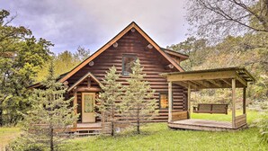 A log cabin with a porch and a swing, surrounded by trees and grass. - Splendid Family Cabin w/ Hot Tub & Grill! (Lake City)