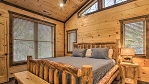 Une chambre dans une cabane en bois, avec un grand lit, un banc et une table de chevet avec une lampe.