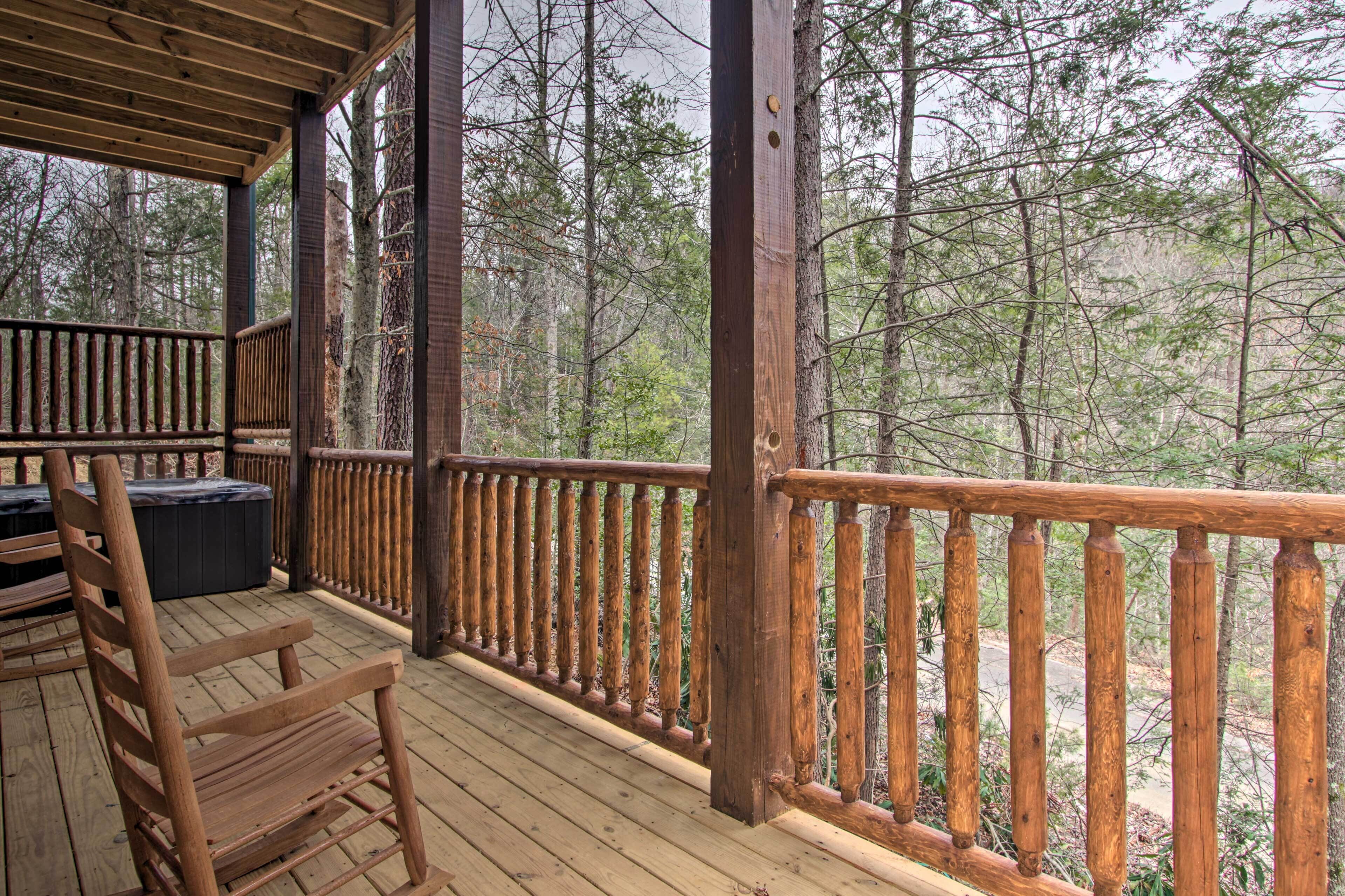A wooden deck with a railing, a bench, and a hot tub.