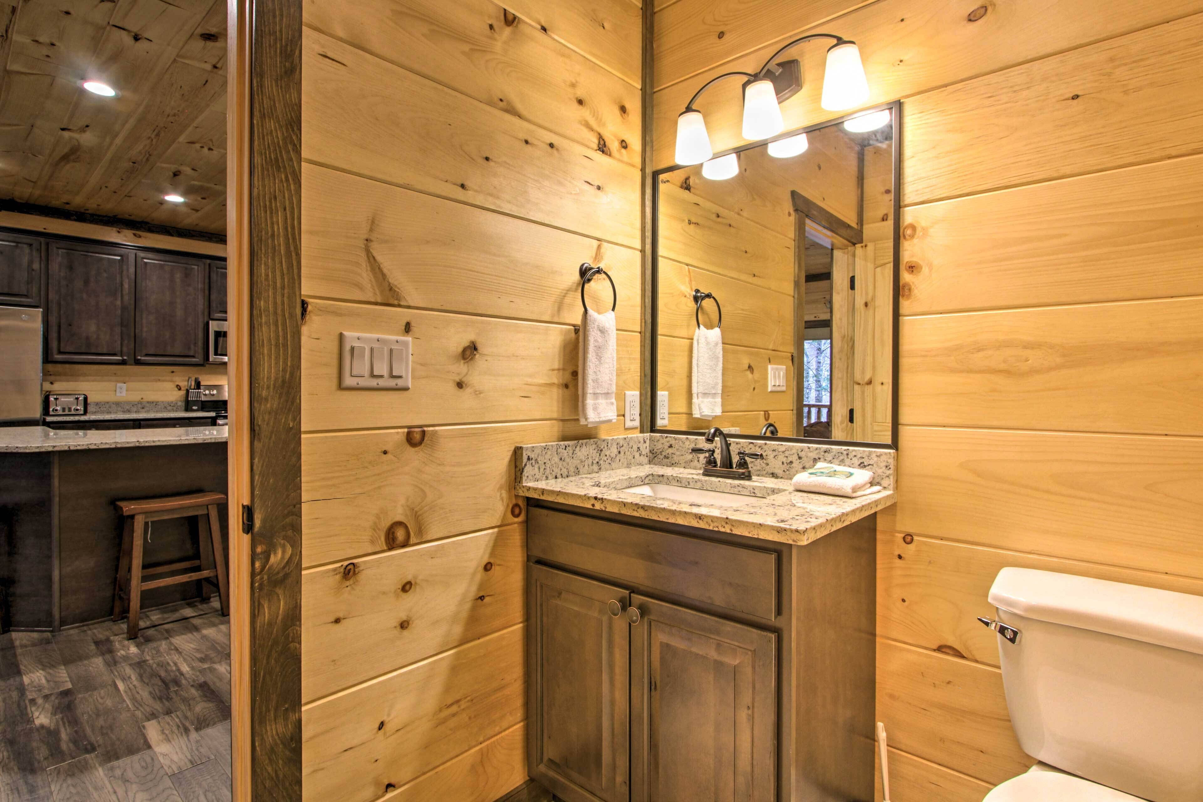 A wooden-paneled bathroom with a sink, mirror, and toilet.