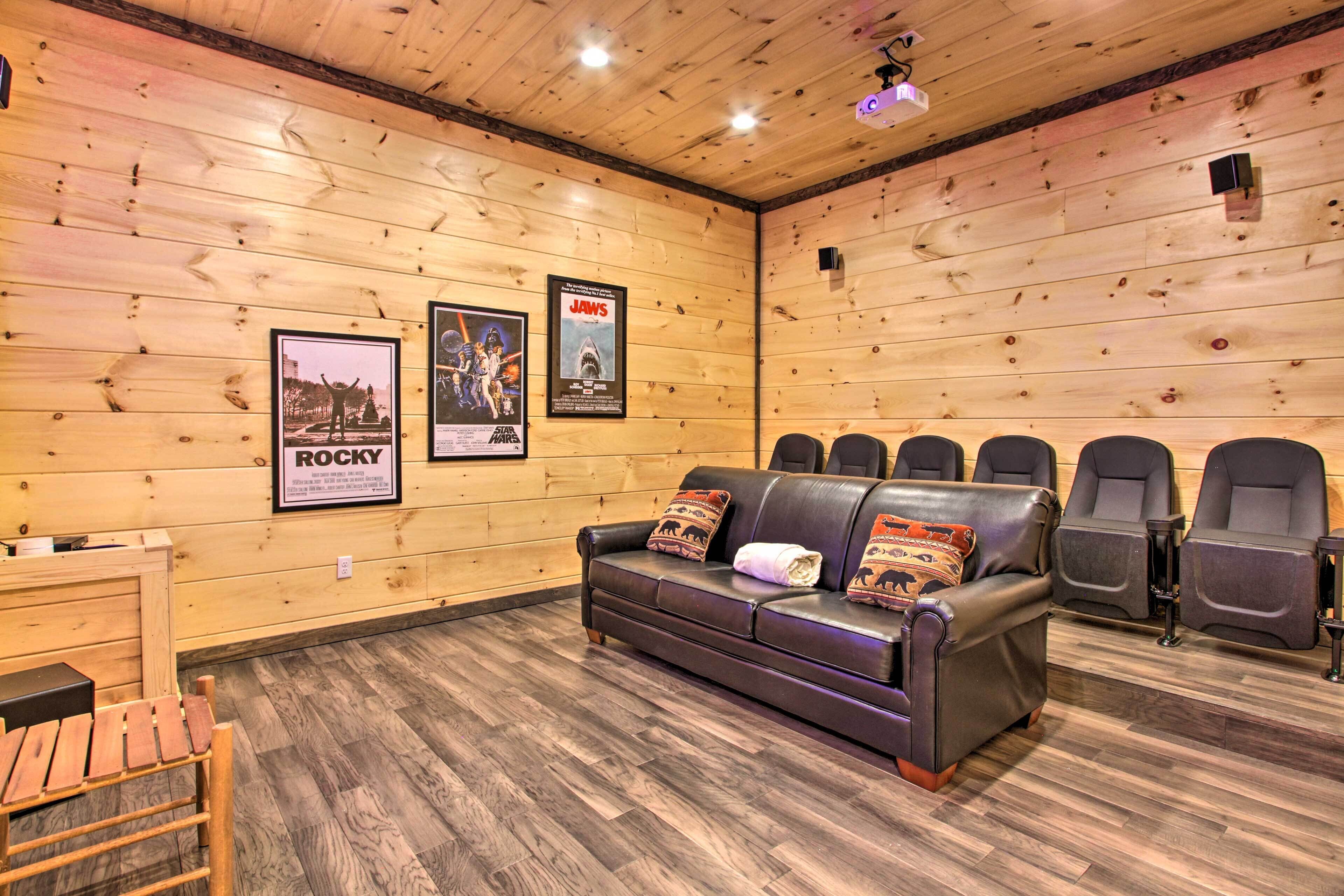 A wooden-paneled room with a sofa, chairs, and posters on the walls.