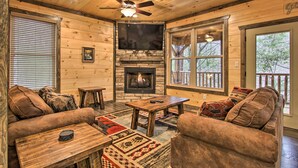 Un intérieur de chalet chaleureux avec une cheminée, des meubles en bois et de grandes fenêtres.