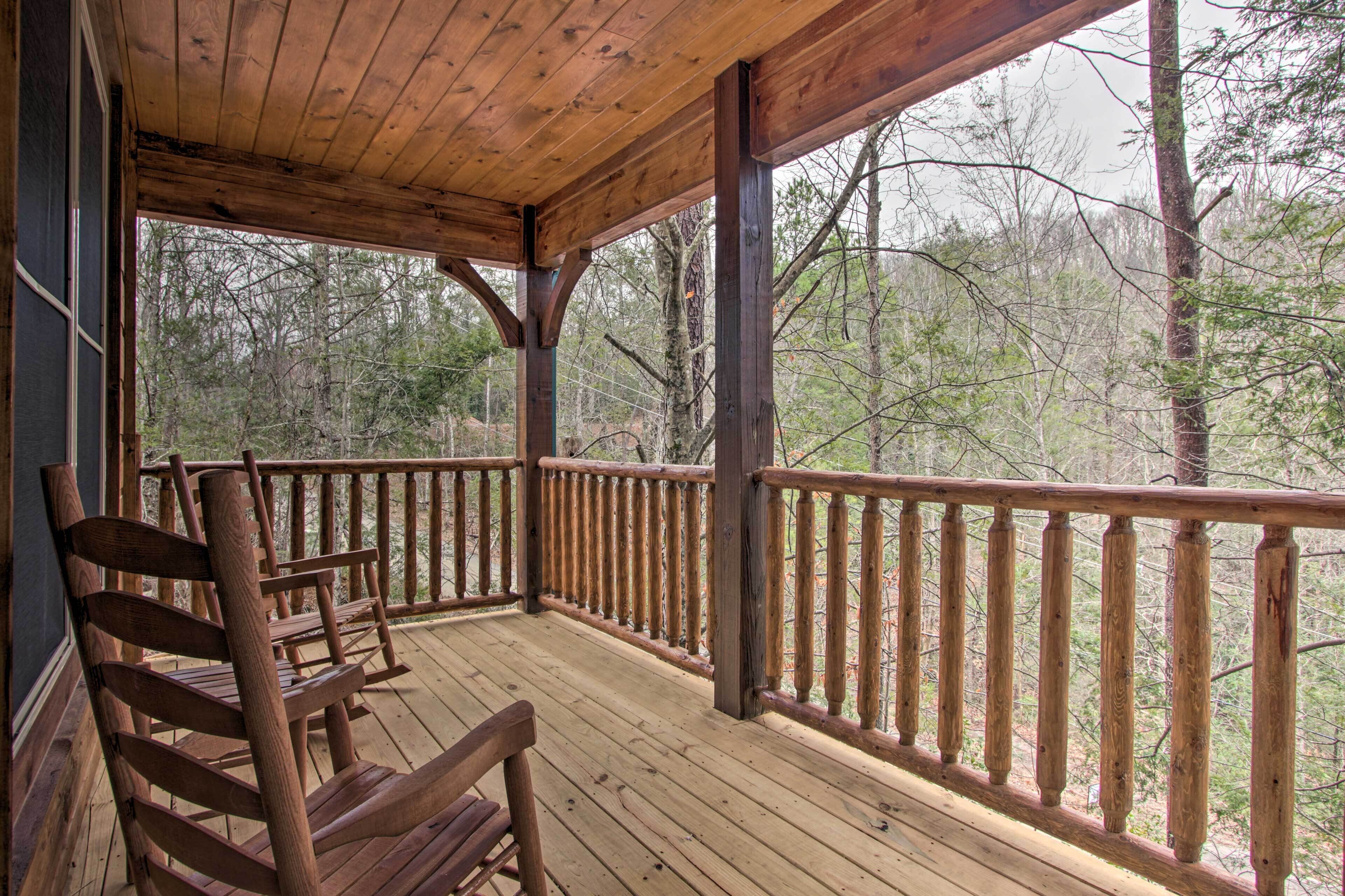 A wooden deck with a railing, a bench, and a view of a forest.