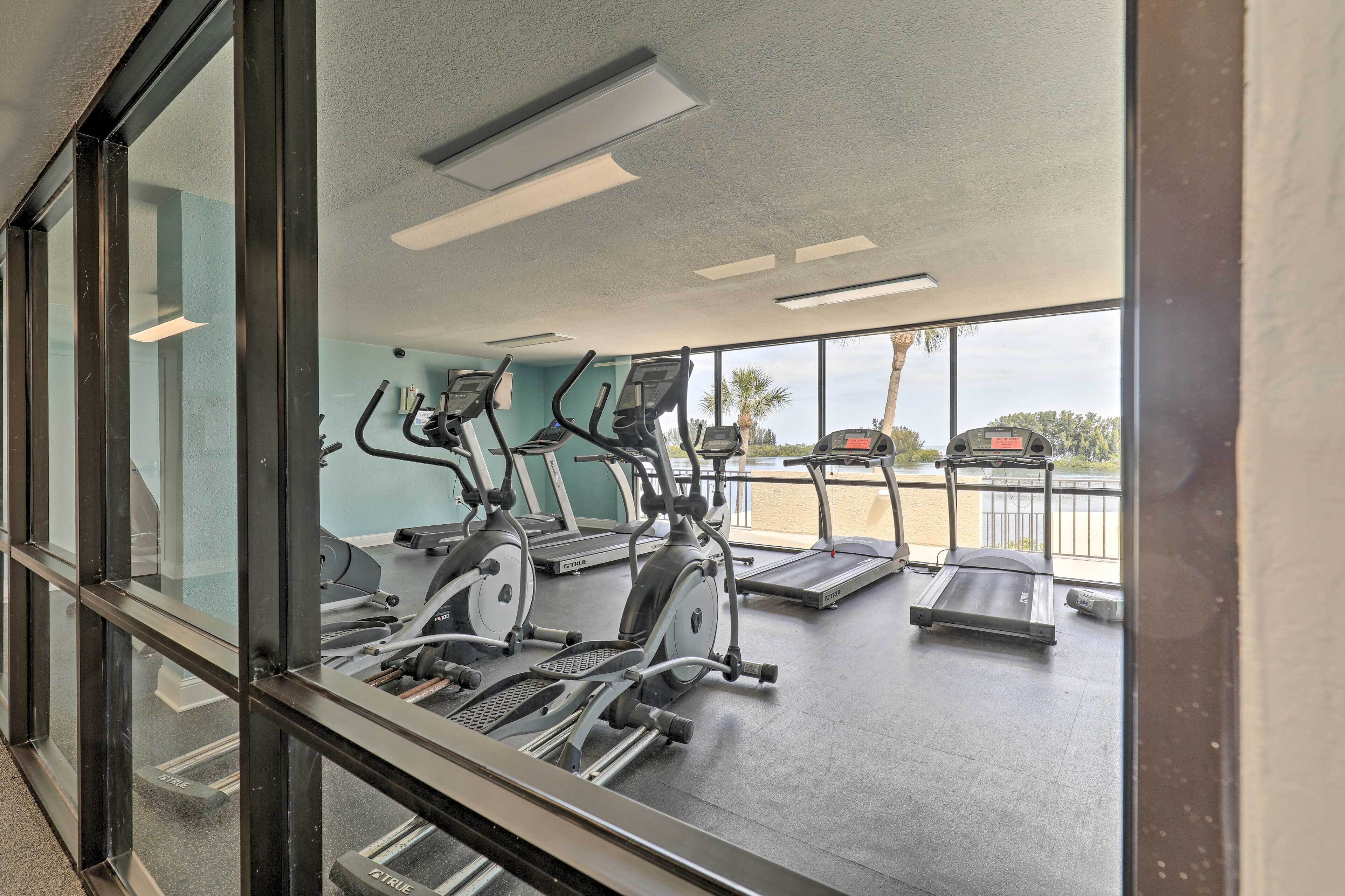 Une salle de sport équipée de tapis de course, de vélos elliptiques et d’un banc de musculation.
