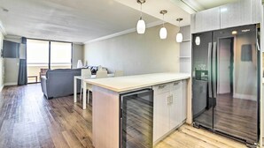 A modern kitchen with a built-in refrigerator, a dining area with a gray sofa, and pendant lights. - Waterfront Condo: Resort Pool, Tennis & Beach (Hudson)