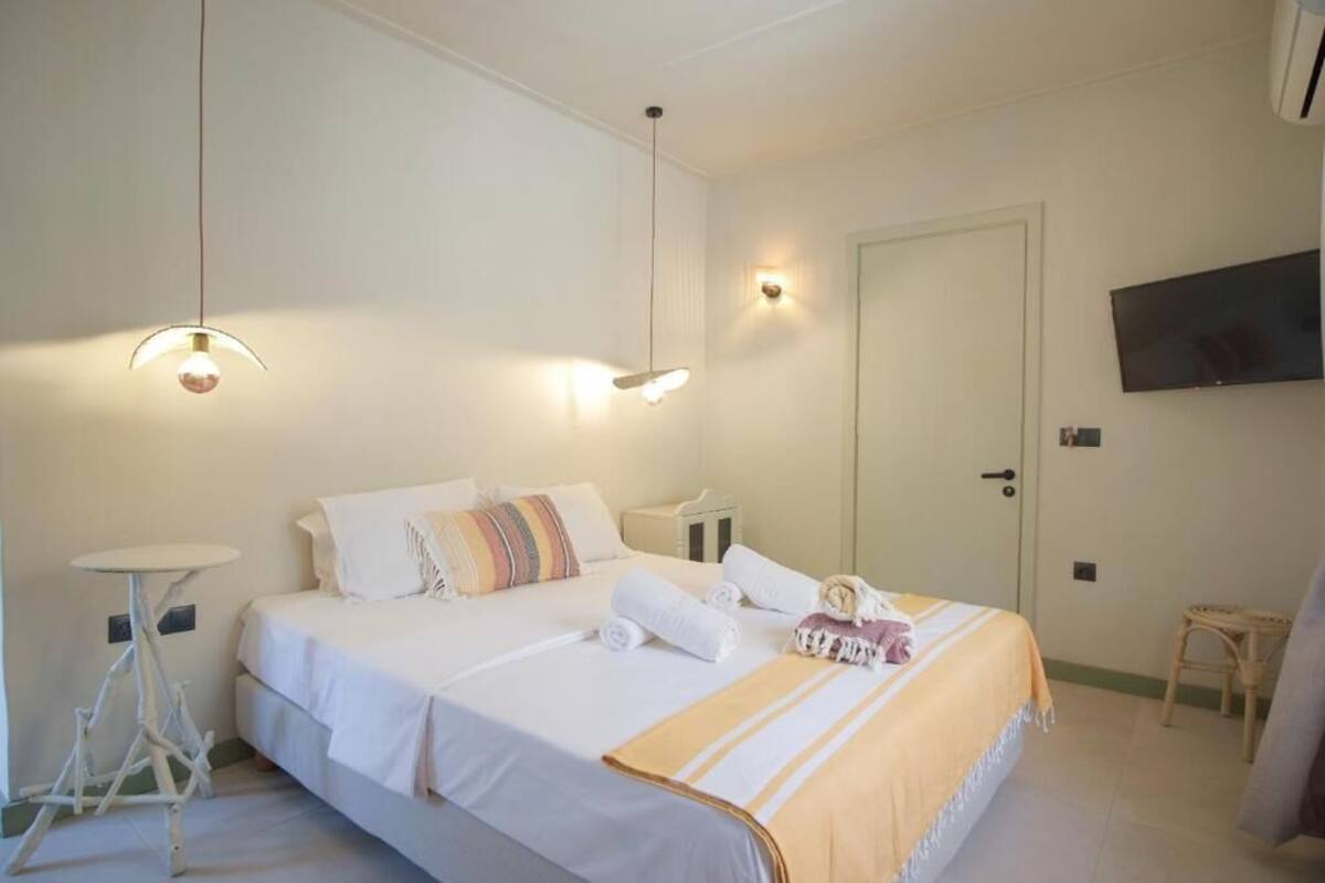 A hotel room with a bed, bedside tables, a television, and a door.