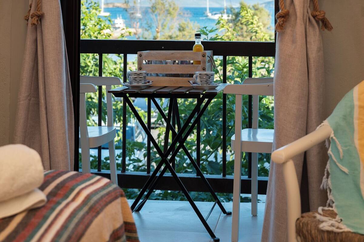 A balcony with a table, chairs, and a view of the sea.