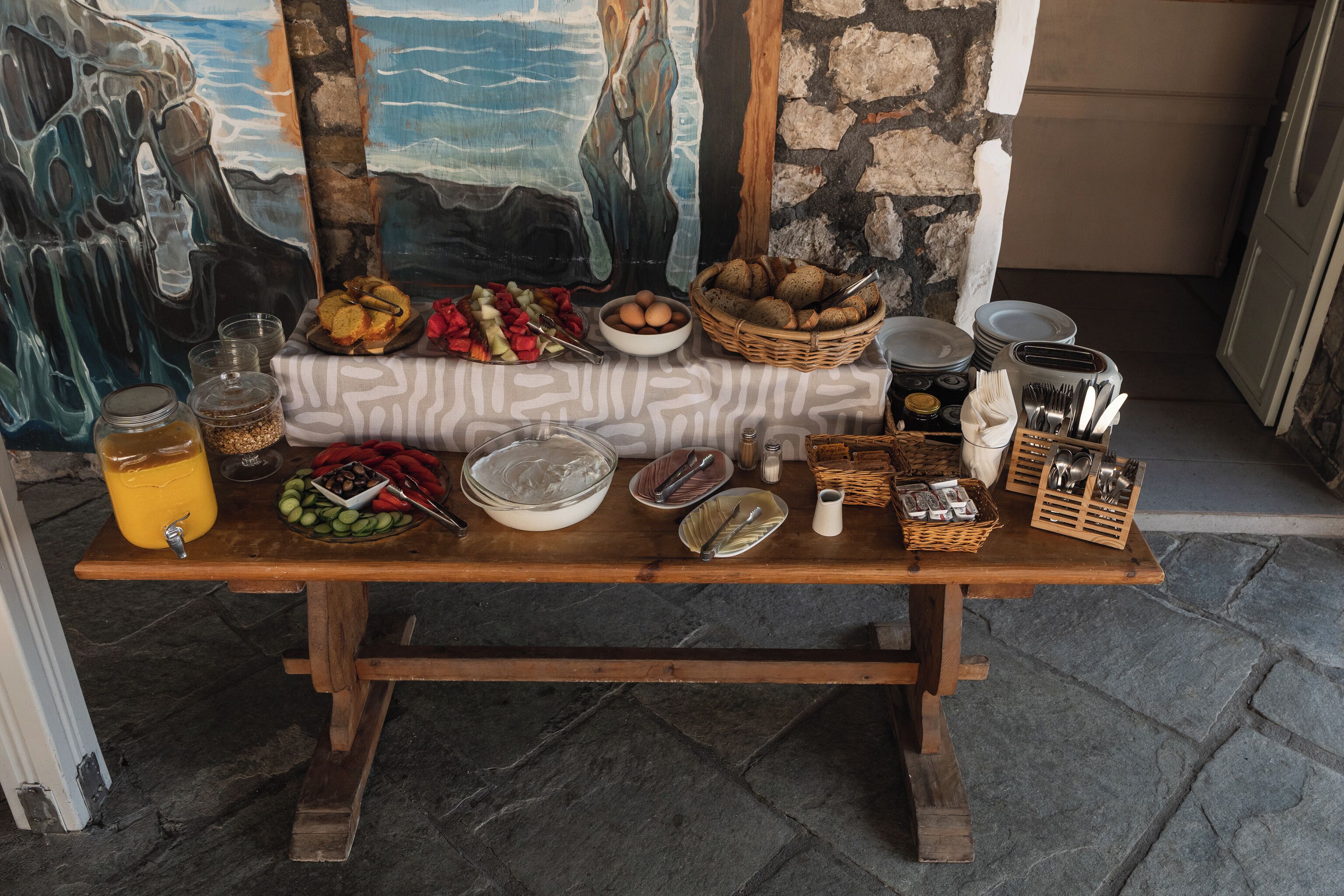 Une table en bois sur laquelle sont disposés divers aliments, des ustensiles de cuisine, et un tableau en arrière-plan.