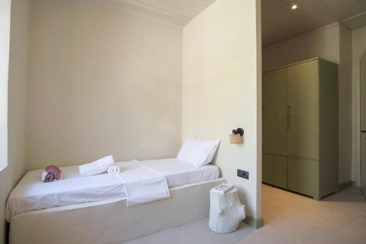A bedroom with two beds, a wardrobe, and a small table with a book.