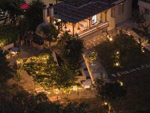 A courtyard with outdoor seating, a covered area, and a building with a tiled roof. - Filanthi The Project (Pylos-Nestoras)
