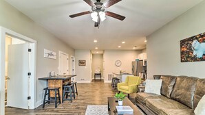 A spacious living room with a brown leather sofa, a yellow armchair, and a dining area with a bar. - Bowling Green Apartment in the Heart of Town! (Bowling Green)