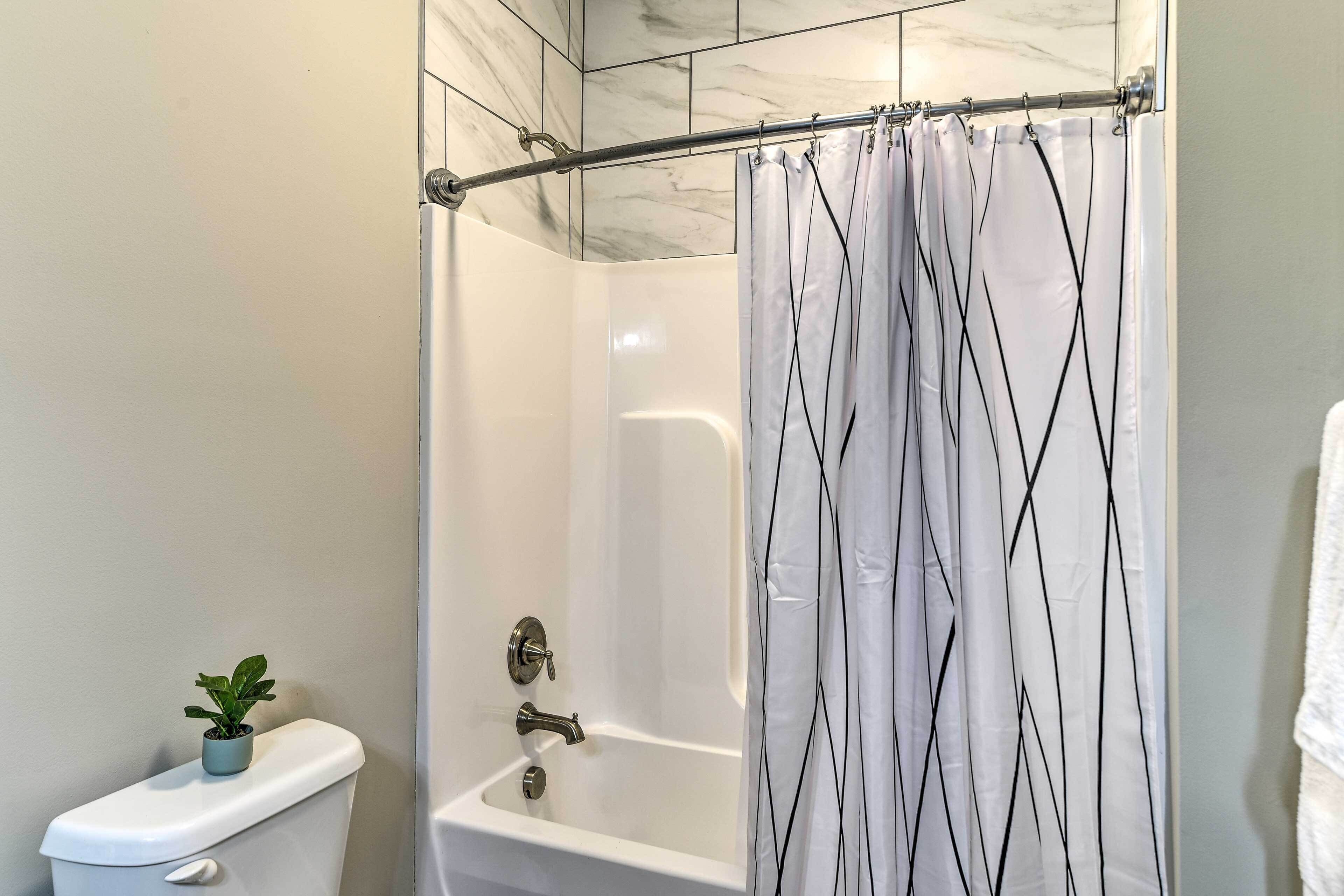 A bathroom with a shower curtain, a toilet, and a potted plant.