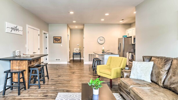 A modern living room with a wooden bar, yellow armchair, and a brown leather sofa. - Bowling Green Apartment in the Heart of Town! (Bowling Green)