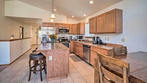 A modern kitchen with wooden cabinets, stainless steel appliances, and a central island with bar stools.