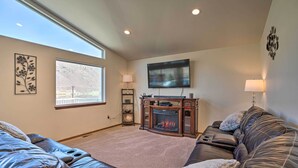 A living room with a fireplace, leather sofas, a flat-screen TV, and a large window with a mountain view.