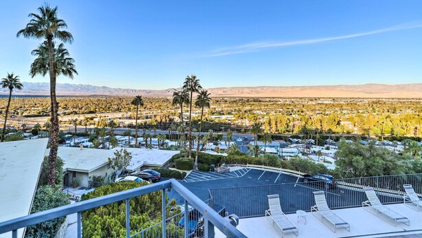 A residential area with palm trees, a parking lot, and a clear view of distant mountains. - Mtn-view Balcony + Pool Access: Palm Springs Gem (Palm Springs)