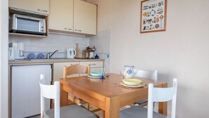 Cocina compacta con microondas, refrigerador y una mesa de comedor con sillas.