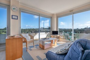 Un vaste balcon offrant une vue sur le panorama urbain, aménagé avec un canapé, une table et un téléviseur.