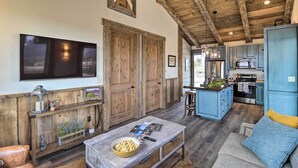 Eine rustikale Küche mit Holzsäulen, einem Essbereich mit einer Holzbank und einem an der Wand montierten Fernseher.