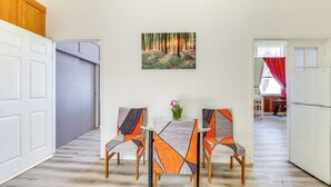 Ein Essbereich mit Tisch und Stühlen, einem Bild an der Wand und Blick in einen anderen Raum.
