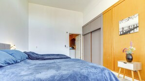 Ein Schlafzimmer mit einem großen Bett, einem Nachttisch, einem Holzschrank und einem kleinen Tisch mit einer Vase.