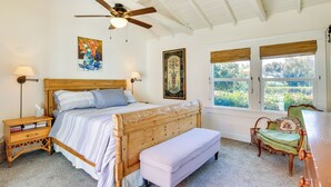 Une chambre à coucher avec un lit en bois, un banc, une chaise et un ventilateur de plafond.