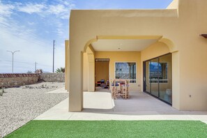 A modern building with a patio area featuring a table and chairs, a glass door, and a view of the surrounding landscape. - Unique Las Cruces Home w/ Patio + Gas Grill! (Las Cruces)