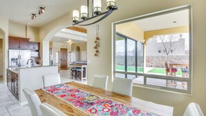 A spacious kitchen with modern appliances, a dining area with a wooden table and chairs, and a large window offering a view of the outdoors. - Unique Las Cruces Home w/ Patio + Gas Grill! (Las Cruces)