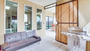A modern kitchen with a sliding glass door, a gray sofa, and a stainless steel grill. - Unique Las Cruces Home w/ Patio + Gas Grill! (Las Cruces)