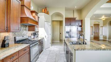 A spacious kitchen with granite countertops, stainless steel appliances, and wooden cabinetry.