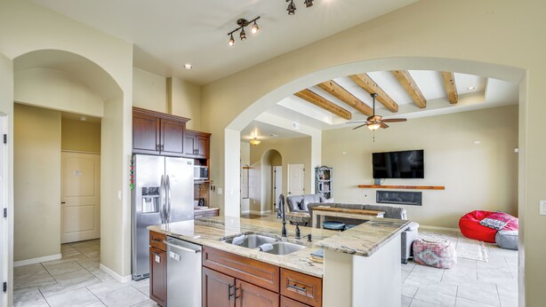A spacious kitchen with a central island, built-in appliances, and an open layout leading to a living area with a TV and seating. - Unique Las Cruces Home w/ Patio + Gas Grill! (Las Cruces)