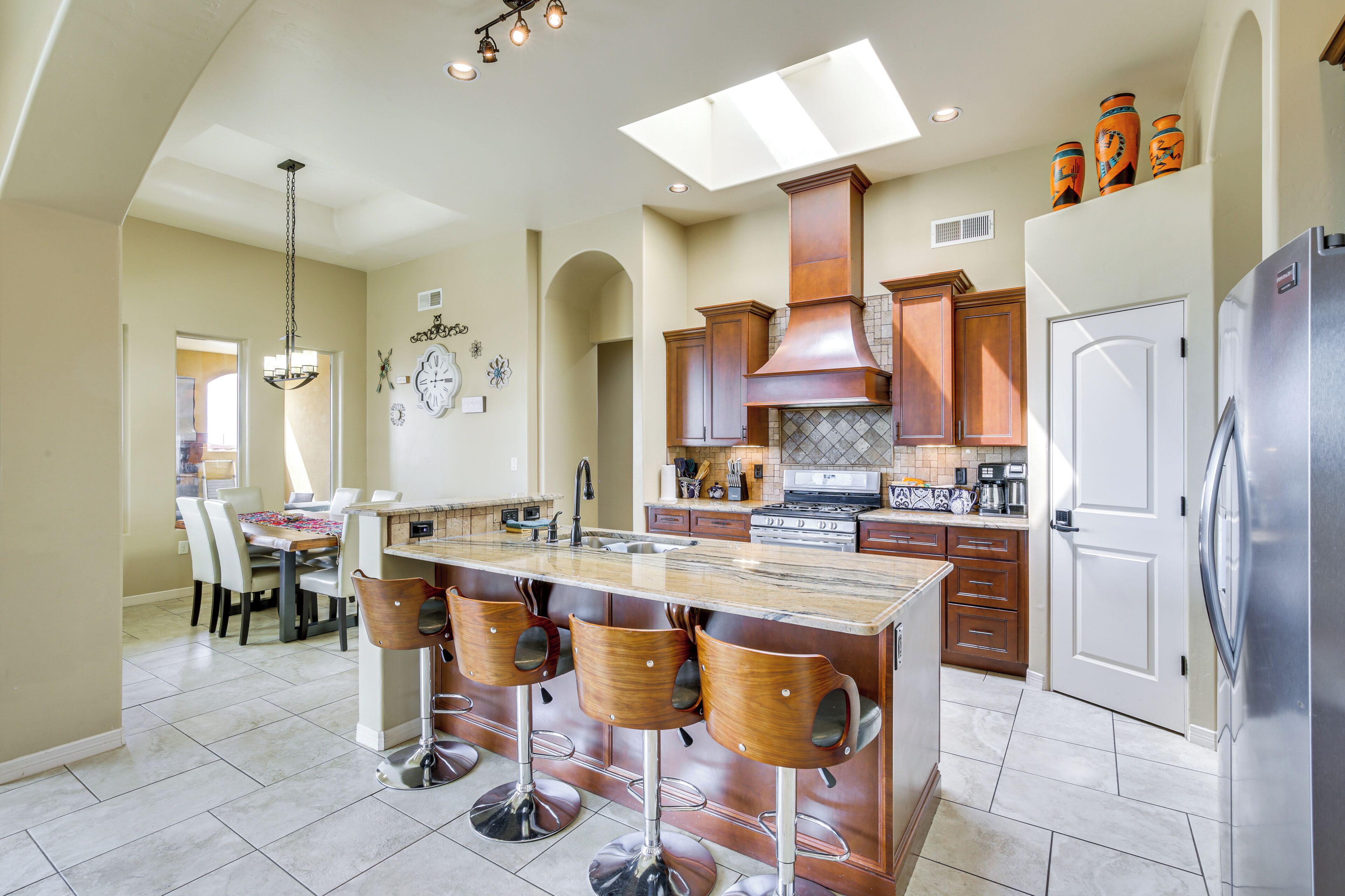 A spacious kitchen with a central island, bar stools, and a modern stove.