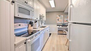 A modern kitchen with white cabinets, a built-in microwave, a stove, and a refrigerator. - Summerhouse Villas Condo With Resort Amenities! (Pawleys Island)