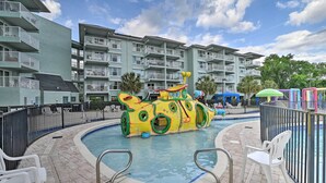 A swimming pool with a submarine-themed water feature, surrounded by a brick deck and white chairs. - Summerhouse Villas Condo With Resort Amenities! (Pawleys Island)