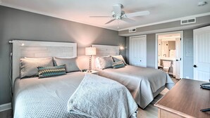 A hotel room with two beds, a ceiling fan, a nightstand with a lamp, and a view into the bathroom. - Summerhouse Villas Condo With Resort Amenities! (Pawleys Island)