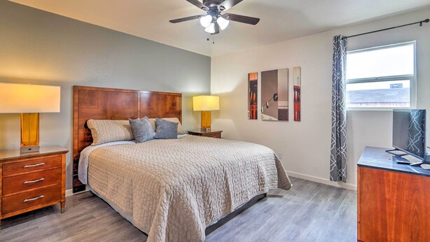 A bedroom with a bed, bedside tables, a ceiling fan, a window with curtains, and artwork on the wall. - Odessa Apartment Near Parks, Shops & Dining! (Odessa)