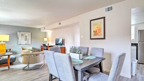 A modern living room with a dining area, a sofa, a TV, and a kitchen in the background. - Odessa Apartment Near Parks, Shops & Dining! (Odessa)