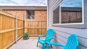 A backyard with a wooden fence, two turquoise chairs, and a small bush. - Odessa Apartment Near Parks, Shops & Dining! (Odessa)