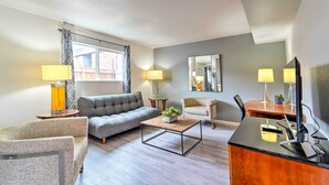 A modern living room with a grey sofa, a wooden coffee table, a desk with a computer, and two lamps. - Odessa Apartment Near Parks, Shops & Dining! (Odessa)
