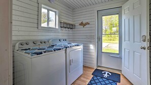 A compact kitchen with a Whirlpool washer and dryer, a window, and a door leading outside. - Cozy Cedarville Cottage - Walk to Lake Huron! (Cedarville)