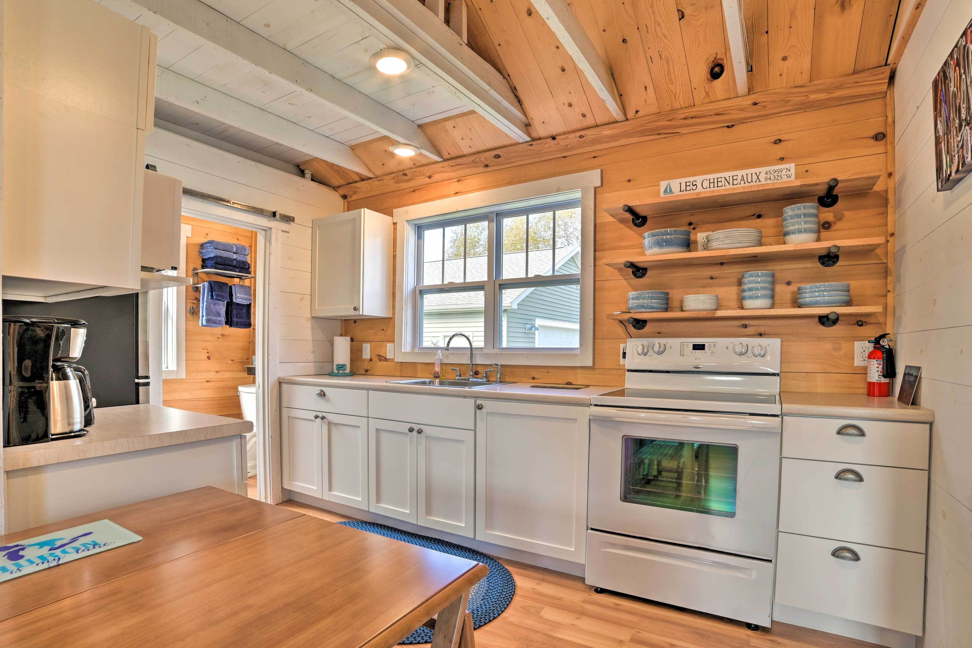A modern kitchen with white cabinets, a built-in oven, and a window.
