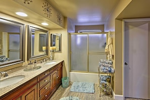 A bathroom with two sinks, a large mirror, a shower, and a towel rack.