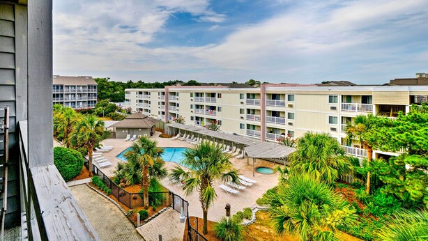 Un hôtel à étages, doté d’une piscine et d’un jardin aménagé avec des palmiers.