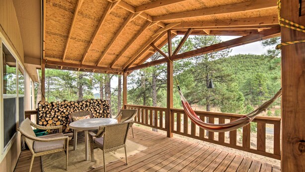 A wooden deck with a table and chairs, a hammock, and a view of trees. - 'hilltop Hideout' w/ Peaceful Mountain Views (Mora)