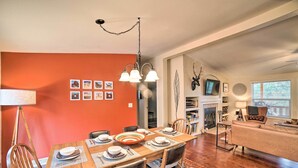 A dining area with a wooden table set for four, surrounded by chairs, and a living area with a sofa and a fireplace. - 'hilltop Hideout' w/ Peaceful Mountain Views (Mora)