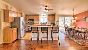 A spacious kitchen with wooden cabinets, a stainless steel refrigerator, and a central island with bar stools. - 'hilltop Hideout' w/ Peaceful Mountain Views (Mora)