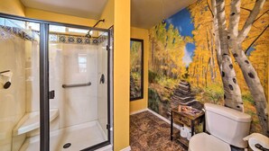 A bathroom with a glass shower enclosure, a toilet, and a mural of birch trees. - 'hilltop Hideout' w/ Peaceful Mountain Views (Mora)
