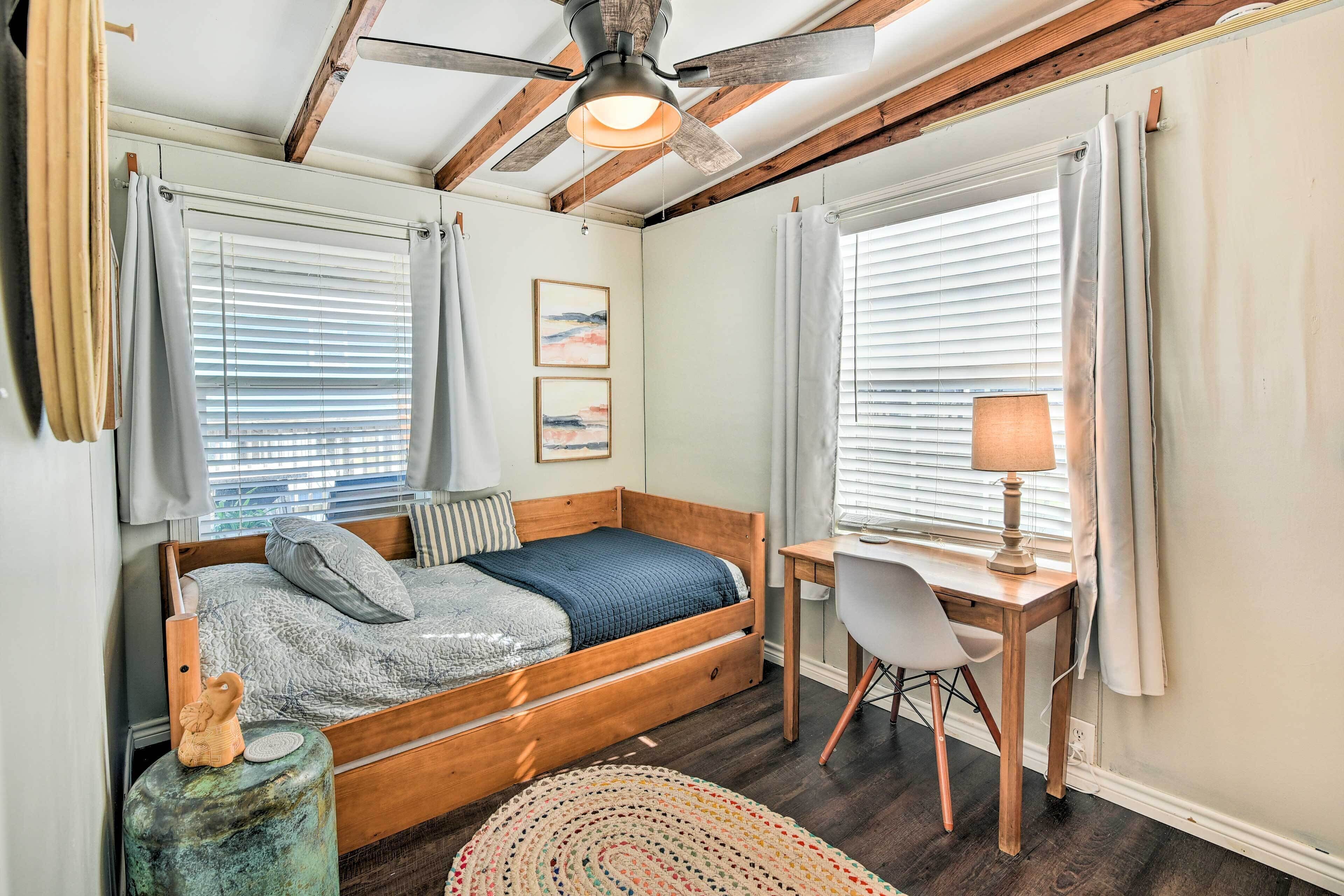 Un dormitorio con una cama de madera, un escritorio y un ventilador de techo.