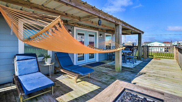 Een houten terras met een hangmat, twee ligstoelen en een bijzettafeltje.